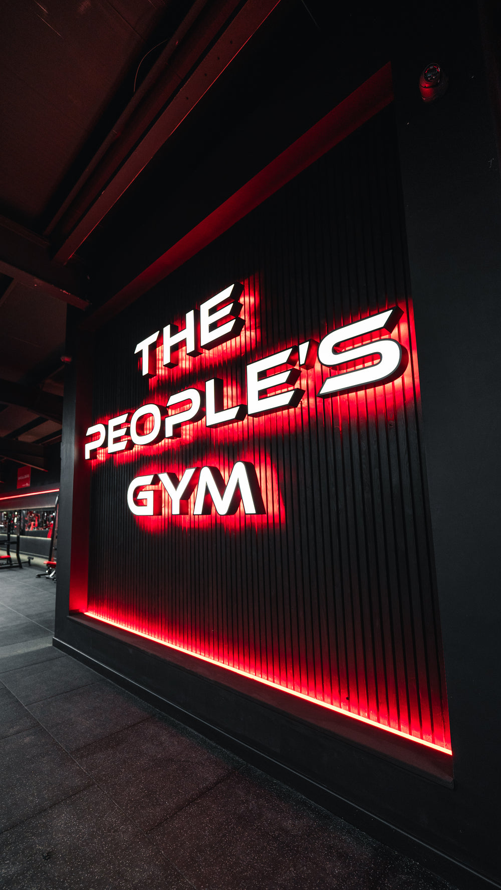 Dark wall panelling with illuminated gym signage and red accent lighting
